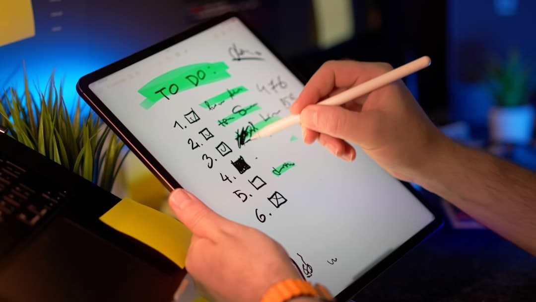 Tablet checklist digital notes productivity planning concept with hand writing and crossing out tasks using stylus in modern workspace