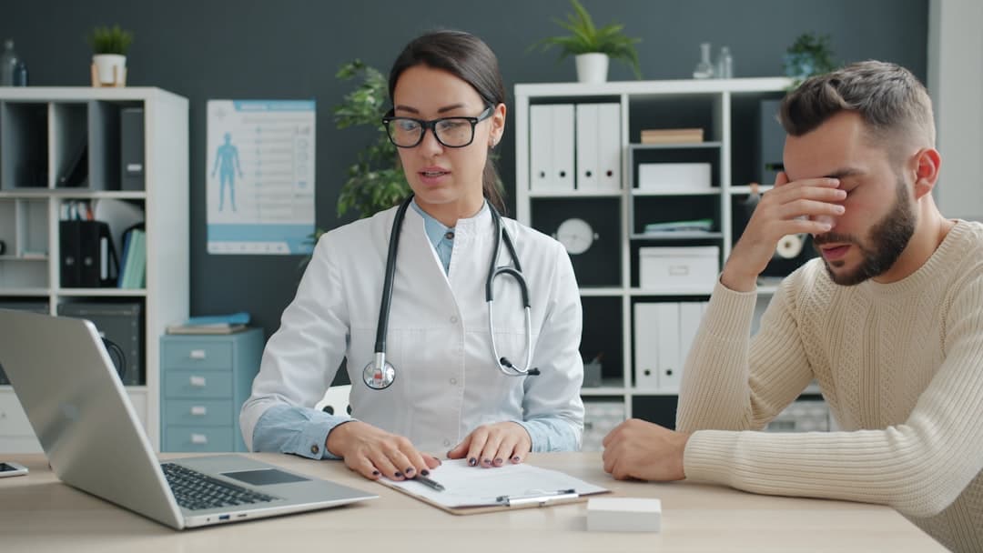 Caring doctor holding patient's hand after giving bad news talking in hospital office expressing support showing laptop screen. People and emotions concept.