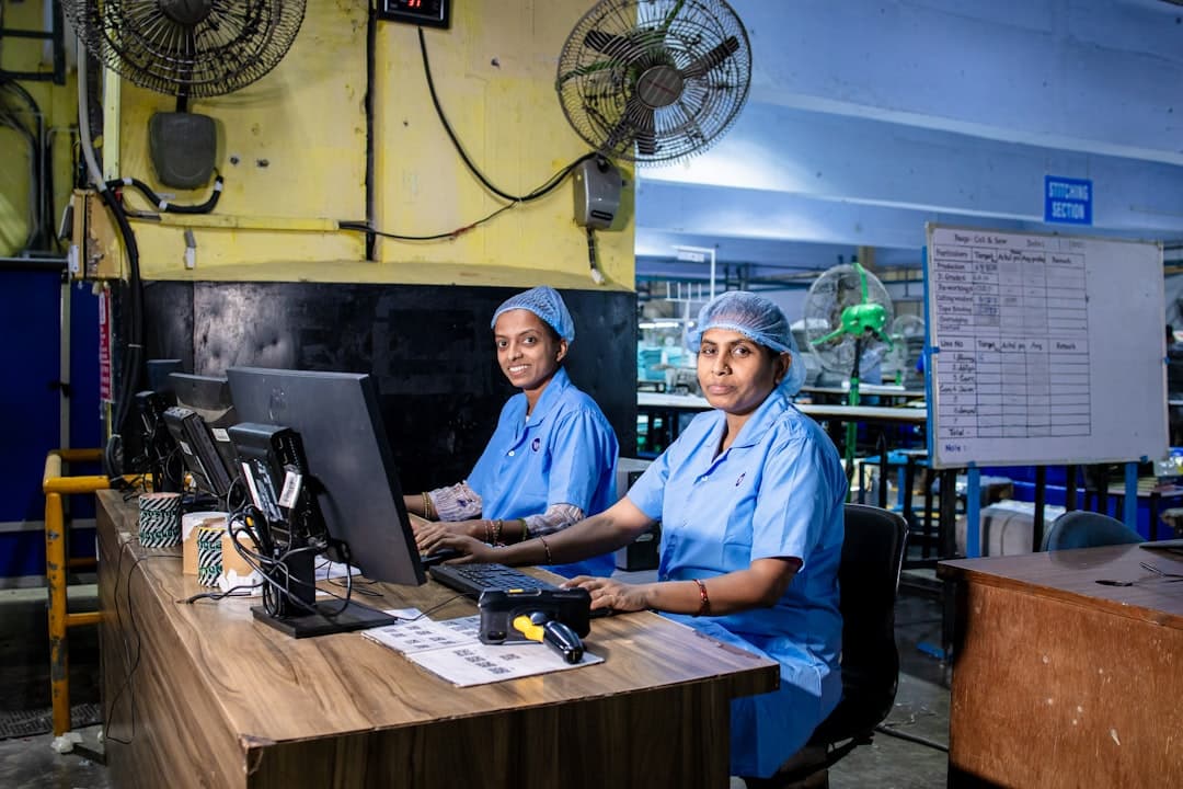 Factory workers in uniform are operating computers.